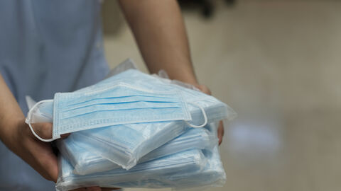 Eine Person hält eingepackte Stapel von medizinischen Masken