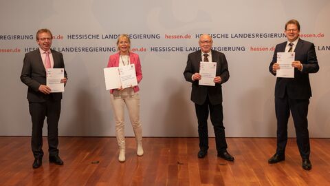 Digitalministerin Sinemus steht gemeinsam mit den Vertragspartnern nebeneinander und hält das unterzeichnete Eckpunktepapier in der Hand. Alle lächeln in die Kamera.