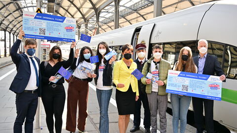 Europaministerin Puttrich mit Jugendlichen und Vertretern der Deutschen Bahn vor einem ICE. Europaflagen und Werbe-Tickets zu "Gewinne dein Interrail-Ticket" in den Händen.