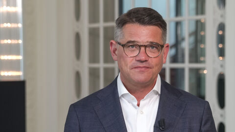 Ministerpräsident Boris Rhein steht vor einer Tür. Er trägt ein schwarzes Sakko und ein weißes Hemd.