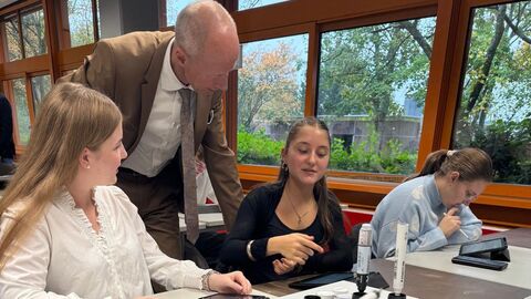 Bildungsminister spricht mit Schülerinnen in einem Klassenzimmer.