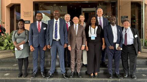 Mehrere Personen stehen vor Gebäude und lächeln in Kamera