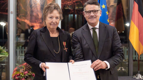 Frau und Mann blicken in Kamera und halten Urkunde in den Händen.