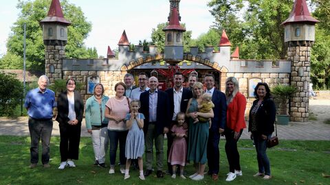 Eine Gruppe um Minister Pentz steht auf einer Wiese im Erlebnispark zum Gruppenfoto aufgestellt.